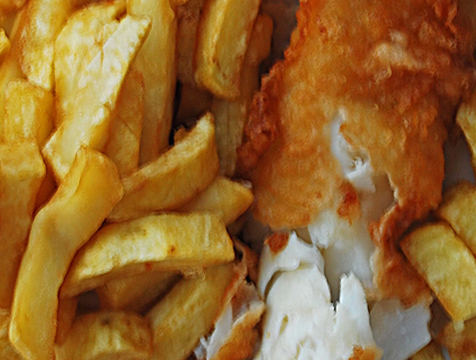 A golden battered fish with a generous portion of chips