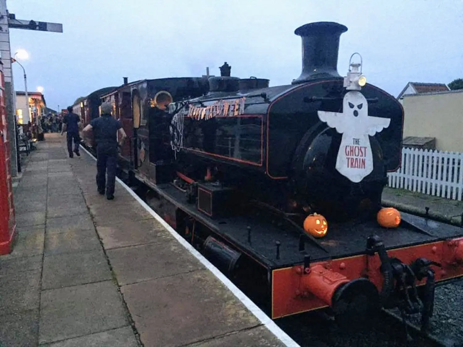 A steam train lit up on the platform at dusk for the Halloween Spooktacular