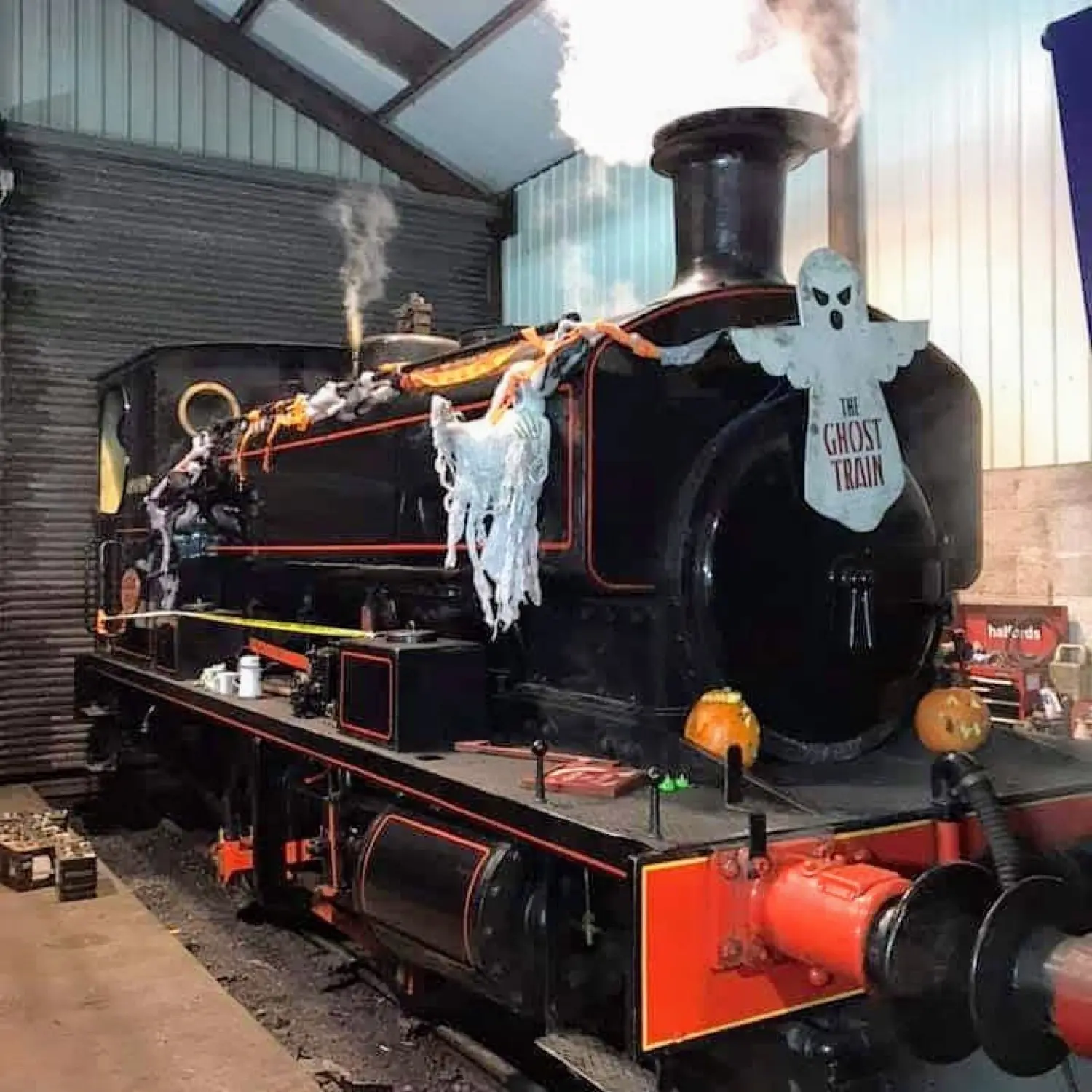 A steam locomotive decorated as the Ghost Train with pumpkins